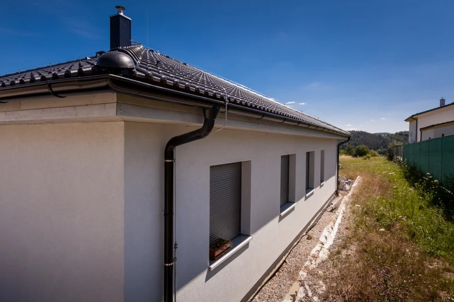 Exteriér – Rodinný dům Levín, roh domu s komínem a okny do zahrady
