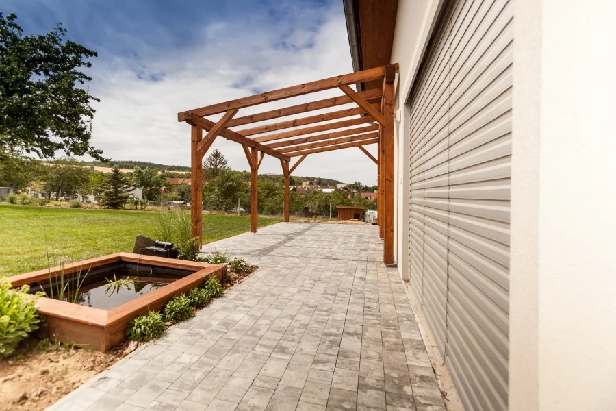 Exteriér – Rodinný dům Všejany, dřevěná pergola nad dlážděnou terasou s okrasným jezírkem